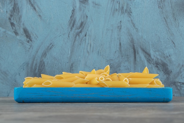 Rohe Penne-Nudeln auf blauem Teller