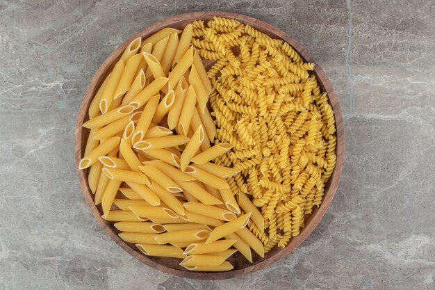 Rohe Penne und Fusilli-Nudeln auf Holzplatte