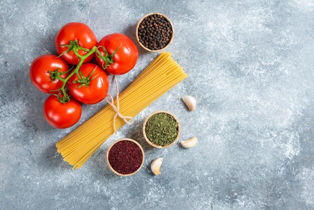 Rohe Spaghetti, Gewürze und Tomaten auf Marmorhintergrund.