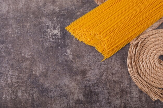 rohe Spaghetti mit Seil Draufsicht auf graue Oberfläche Draufsicht