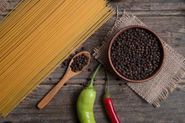 Rohe Spaghetti und eine Schüssel Pfefferkörner auf Holzoberfläche. Hochwertiges Foto