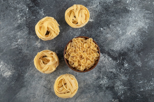 Kostenloses Foto rohe trockene nestnudeln mit farfalle tonde nudeln auf einem marmortisch.