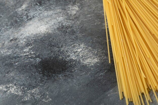 Rohe trockene Spaghetti auf einem Marmortisch.
