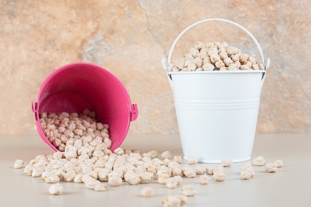 Rohe weiße Erbsenbohnen in einer bunten Tasse auf Beton.