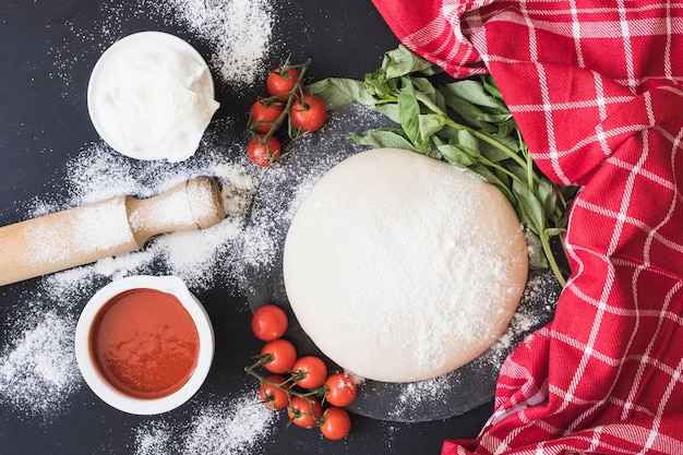 Roher Teig für Pizza mit Bestandteilen auf Küchentheke