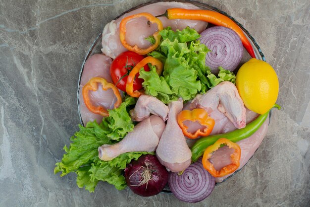 Rohes Hühnerfleisch mit frischem Gemüse auf Marmorhintergrund. Foto in hoher Qualität