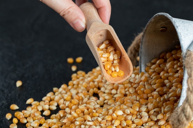 Rohes Popcorn mit Holzlöffel auf einem dunklen