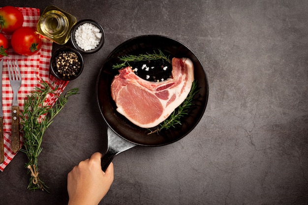 Rohes Schweinekotelettsteak auf der dunklen Oberfläche.