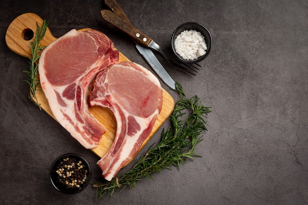 Rohes Schweinekotelettsteak auf der dunklen Oberfläche.