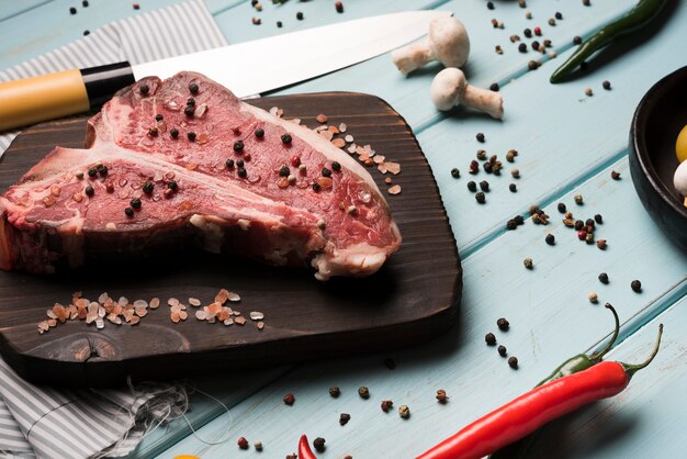 Rohes T-Bone-Steak mit Pfeffer flach legen