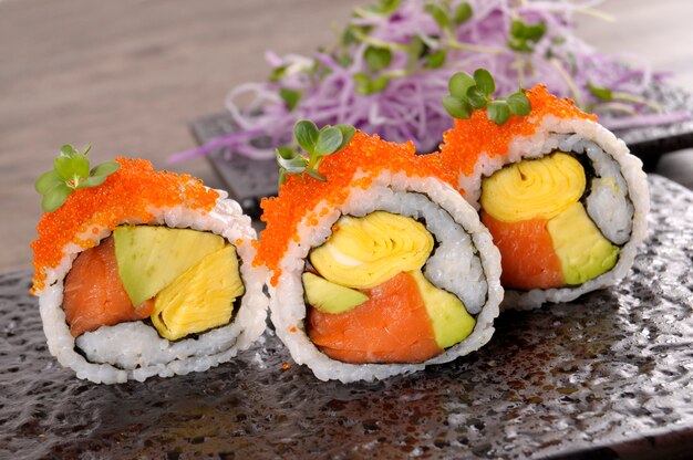 Roll Sushi mit Kaviar auf einem schwarzen Teller