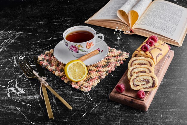 Rollkuchen mit Schokolade und Beeren und einer Tasse Tee.