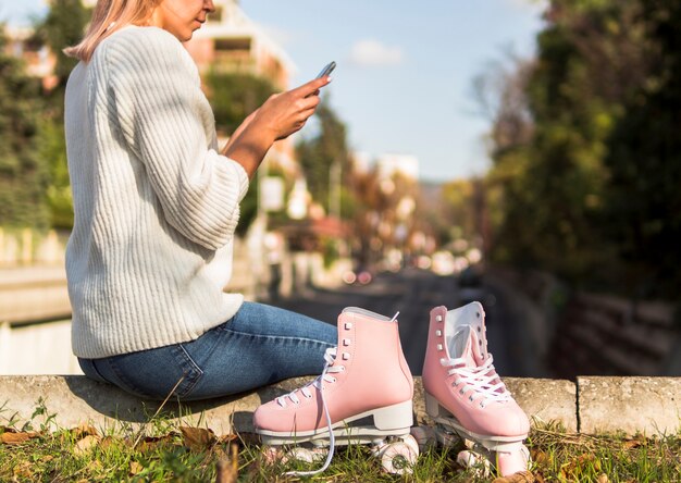 Rollschuhe mit der Frau, die Smartphone betrachtet