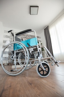Rollstuhl in einem raum ohne personen für patienten mit gehbehinderung. kein patient im zimmer im privaten pflegeheim. therapie mobilitätsunterstützung ältere und behinderte gehbehinderung beeinträchtigung