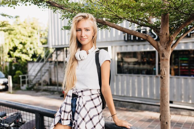 Romantische Frau mit dem langen blonden Haar, das mit interessiertem Gesichtsausdruck aufwirft.