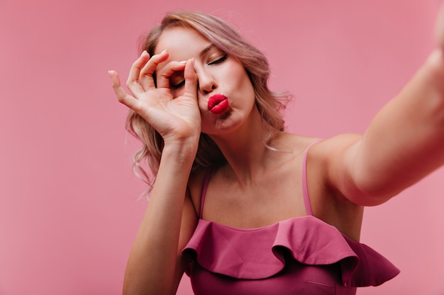 Romantische Frau mit den roten Lippen, die mit küssendem Gesichtsausdruck während des Innen-Fotoshootings posieren