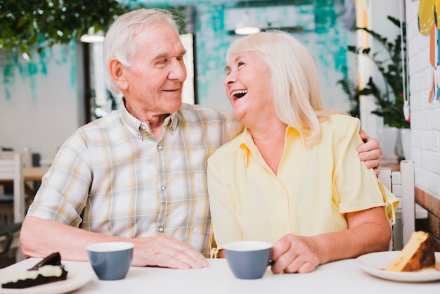 Romantische glückliche reife Paare, die im Café und in der Umfassung sitzen