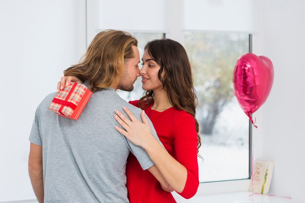 Romantische junge Paare, die vor Fenster sich umfassen