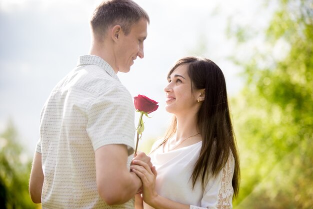 Romantische Kerl, der eine Blume seiner Freundin lächelnd geben