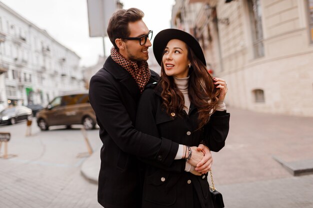 Romantische Momente eines schönen, eleganten, verliebten Paares, das in der Stadt spazieren geht, sich umarmt und die gemeinsame Zeit genießt. Warme Farben. Valentinstag