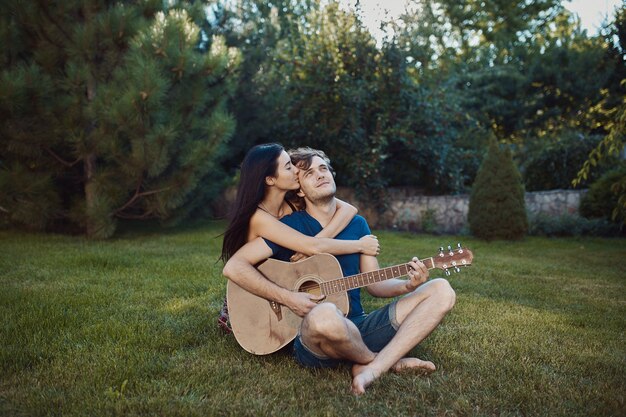 Romantische Paare, die auf dem Gras im Garten sitzen