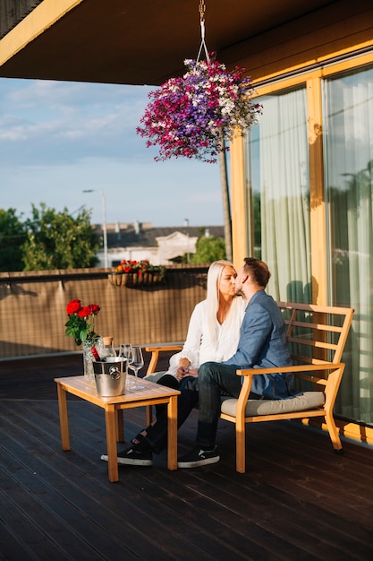 Romantische Paare, die auf der Dachspitze sich küssend sitzen