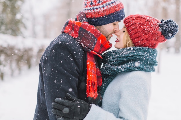 Romantische Paare, die in den Schneeflocken küssen