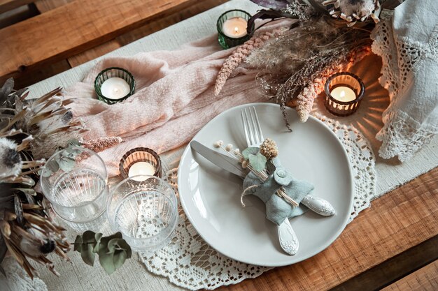Romantisches Gedeck mit brennenden Kerzen und getrockneten Blumen für eine Hochzeit oder Valentinstag.