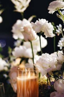 Romantisches hochzeits-tischplatten-layout-dekor mit großen üppigen blumensträußen, darunter weiße rosen, ranunkeln, persische butterblumen, weiße orchideen und kerzen. foto in hoher qualität