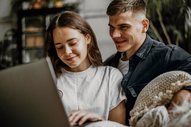 Romantisches junges Paar, das Laptop zusammen durchsucht