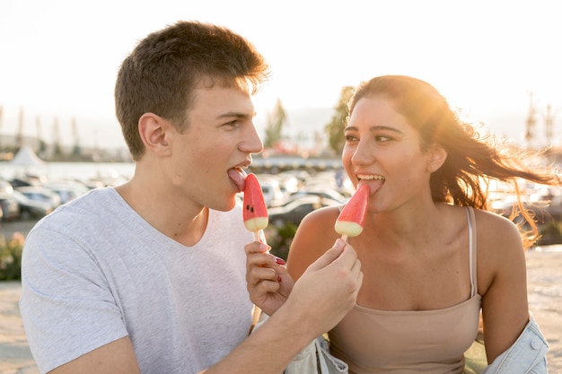 Romantisches paar, das eis am stiel draußen isst