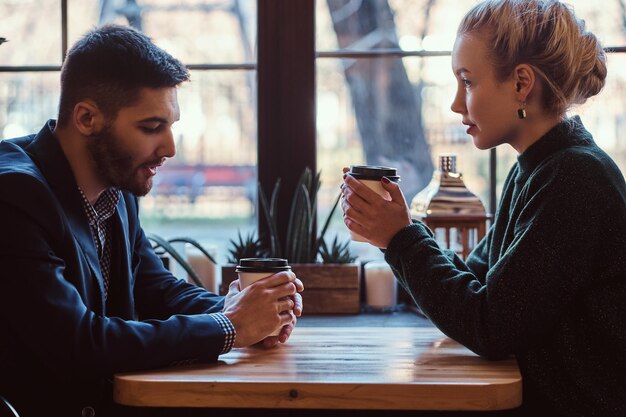 Romantisches Paar im Café trinkt Kaffee und redet. Schöner Mann und schönes Mädchen genießen das Zusammensein.