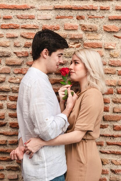 Romantisches Paar umarmte, während es Rose hielt