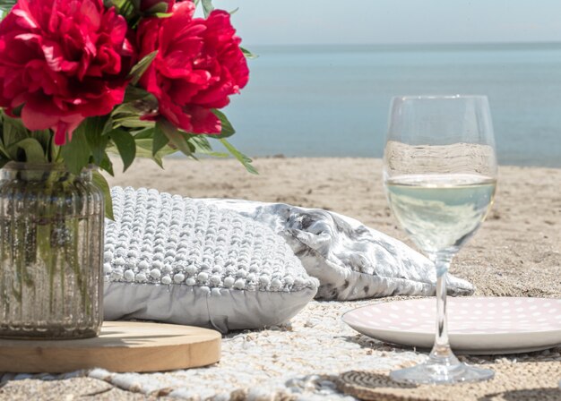 Romantisches Picknick mit Blumen und Gläsern Champagner am Meer. Das Konzept eines Urlaubs.