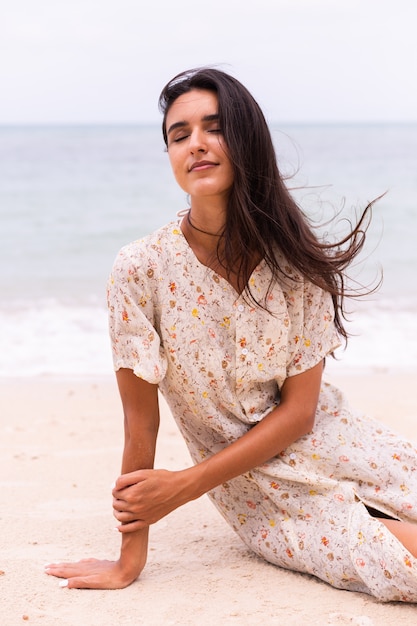 Romantisches Porträt der Frau im langen Kleid am Strand am windigen bewölkten Tag.