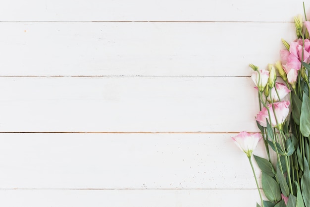 Rosa Blumen auf hölzernem Schreibtisch