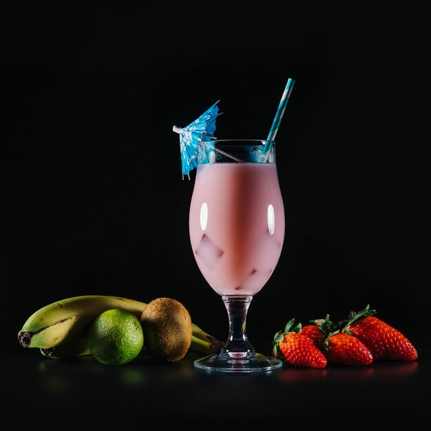 Rosa Cocktail und exotische Früchte auf schwarzem Hintergrund