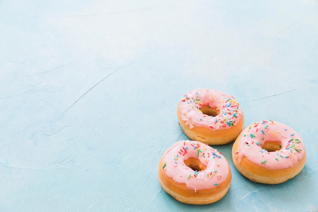 Kostenloses Foto rosa donuts, die mit verziert werden, besprüht auf blauem hintergrund