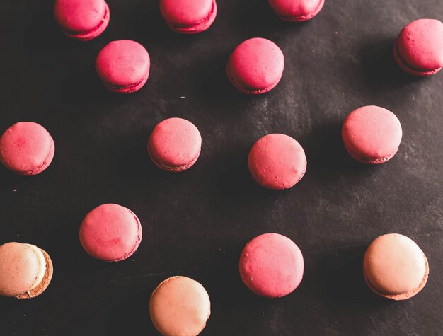 Rosa Erdbeer-Macarons auf schwarzem Hintergrund