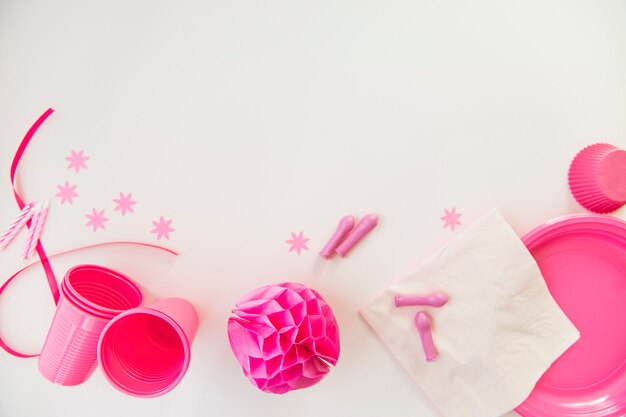 Rosa Kerzen; Kunststoffgläser; Taschentuch; Platten und Bienenwabenpapierball auf weißem Hintergrund