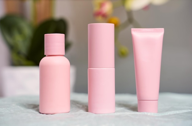 Rosa kosmetikbehälter. kosmetische flaschen der hautpflege auf blumenhintergrund