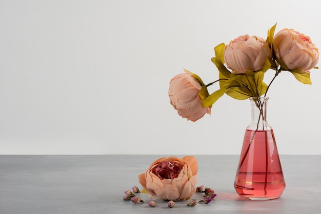 Rosa Pfingstrosenrosenblumen in der Glasvase auf grauem Tisch