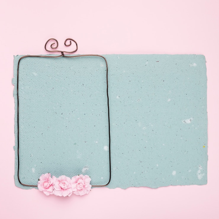 Kostenlose Foto rosen auf verdrahtetem rahmen über dem blauen papier auf rosa hintergrund