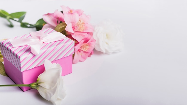 Rosen und rosa Lilienblumen mit Geschenkbox auf weißem Hintergrund