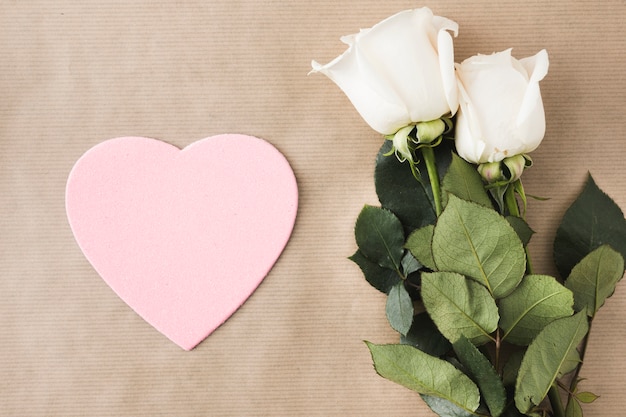 Rosenblumen mit rosa Papierherzen auf Tabelle