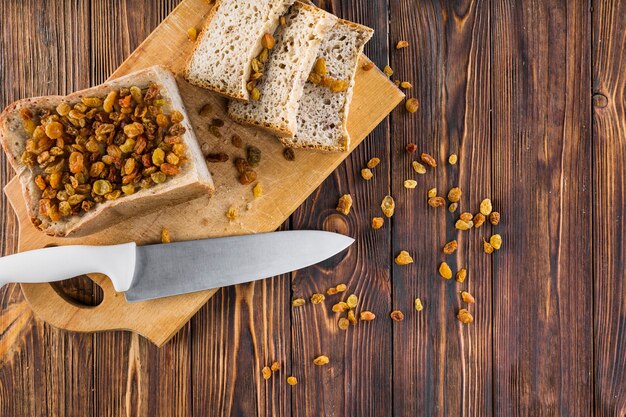 Rosinen auf den Brotscheiben mit scharfem Messer auf hackendem Brett über dem Holztisch