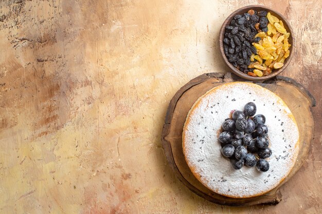 Rosinengrüne und schwarze Rosinen der oberen Nahaufnahme in der Schüssel Kuchen mit Trauben und Puderzucker