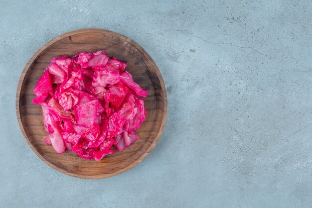 Rot fermentiertes Sauerkraut auf einer Holzplatte, auf dem blauen Tisch.