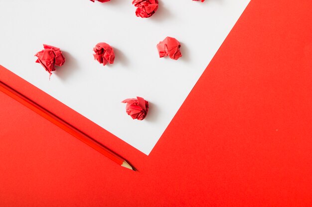 Rot zerknittertes Papier auf weißem und rotem Doppelpapierhintergrund mit Bleistift