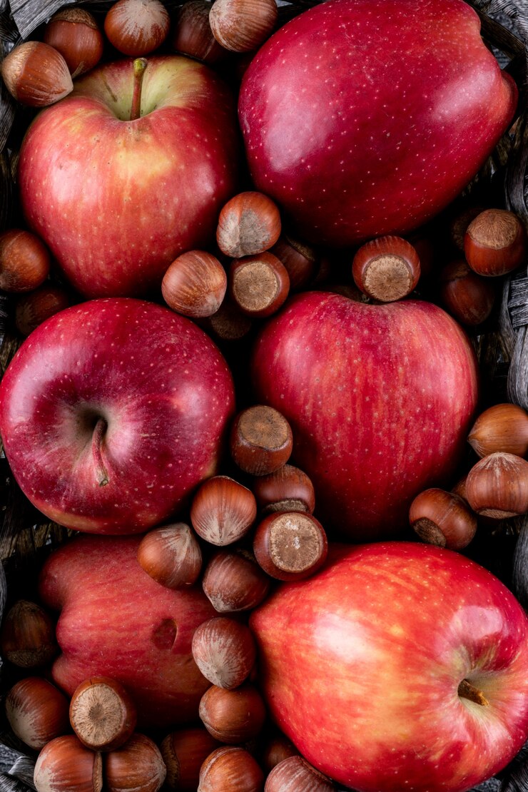 Kostenlose Foto rote äpfel der draufsicht mit nüssen in der vertikalen korbstruktur